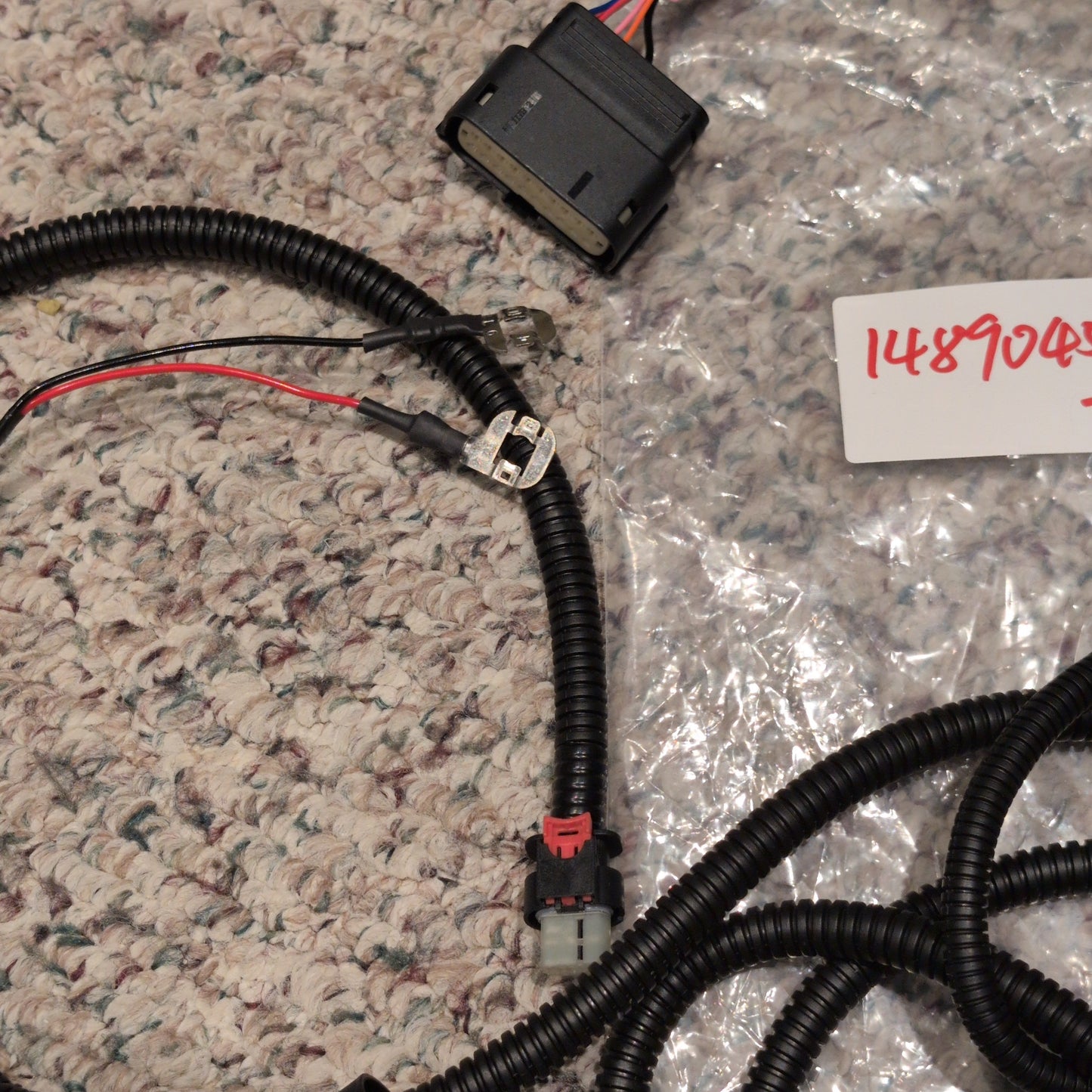 Electrical wiring harness on a textured surface with a label in the background.